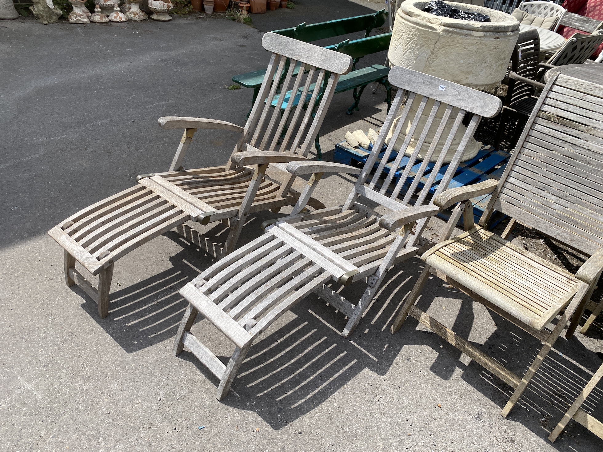A pair of brass mounted weathered teak steamer chairs, labelled P.T.C. Imports, London, width 60cm